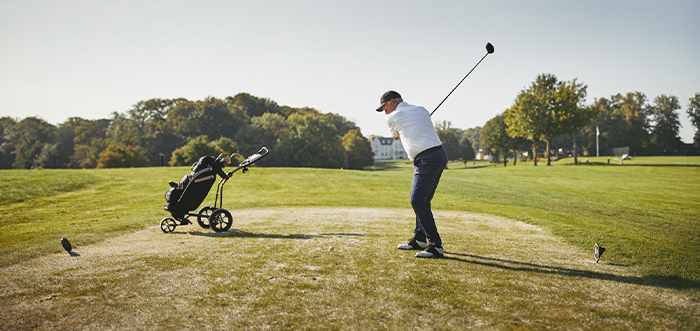 A golfer teeing off on a golf course