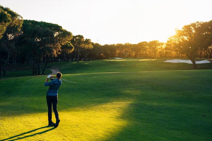 A golfer on a golf course at sunset