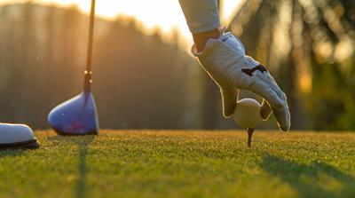 A golfer putting a ball on a tee